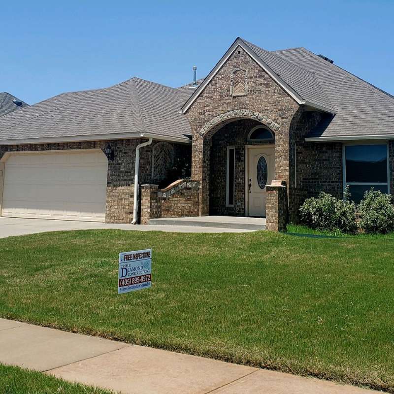 residential home with new asphalt shingle roof and roofers yard sign