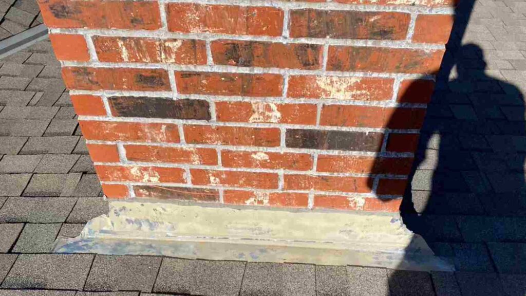 roofer shadow on chimney during roof inspection as part of fall home maintenance tasks