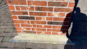 roofer shadow on chimney during roof inspection as part of fall home maintenance tasks