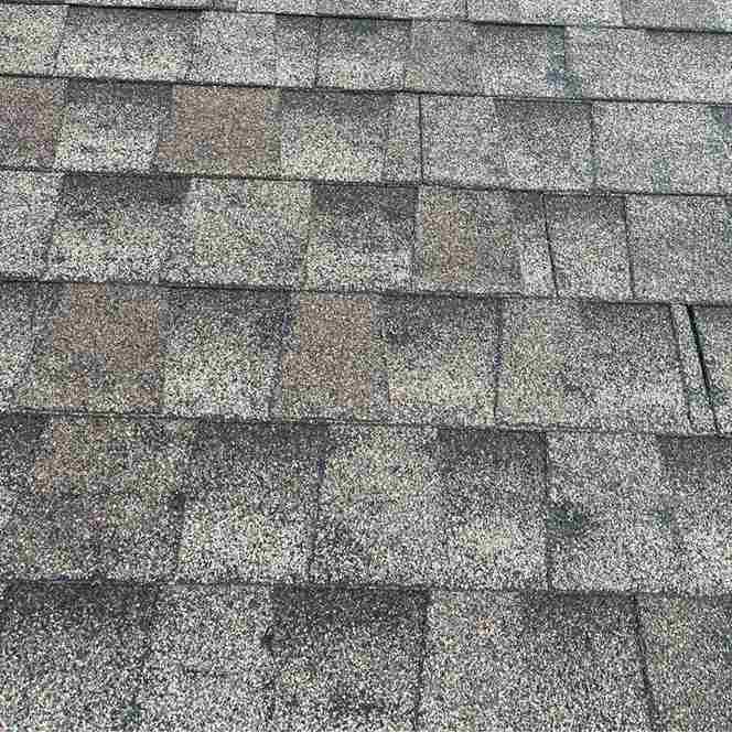 close up of grey roof shingles showing dents and impact marks after hail storm
