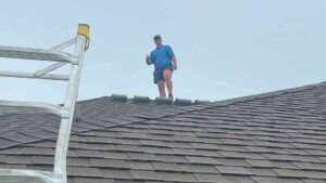 contractor on roof performing fall roof maintenance on home with grey asphalt shingles