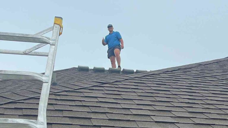 contractor on roof performing fall roof maintenance on home with grey asphalt shingles