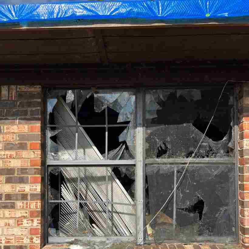 general contractor adding tarp around broken window damaged in tornado