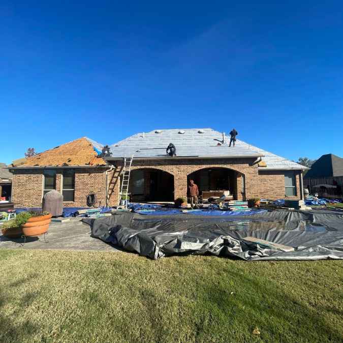 roofer on top of home tearing off old shingles before completing full roof replacement in Moore, OK