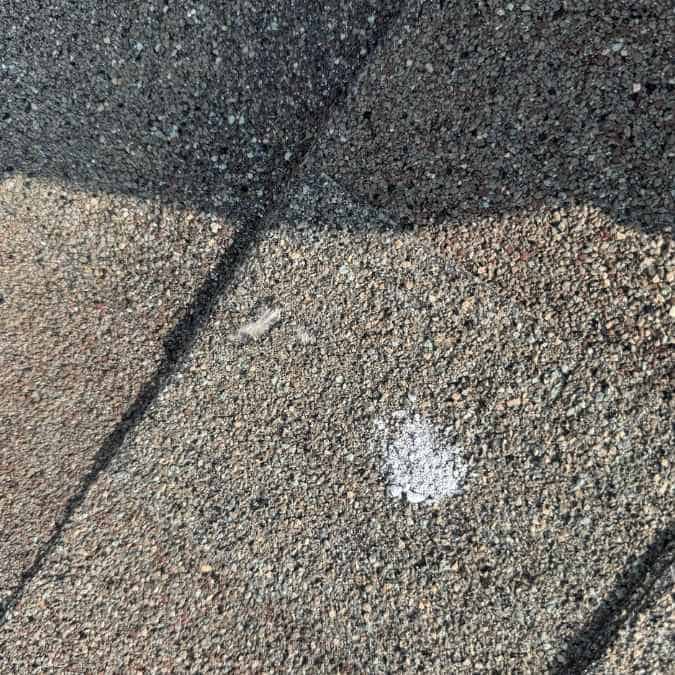 close up of hail impact mark on shingle found during yearly roof inspection