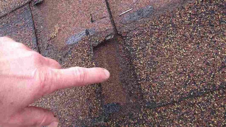 hand pointing to missing shingle on roof asking if insurance covers roof leak repair costs