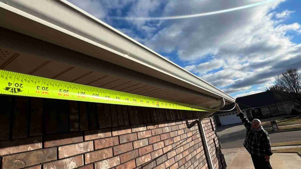 man measuring outside of home getting ready to clean gutters