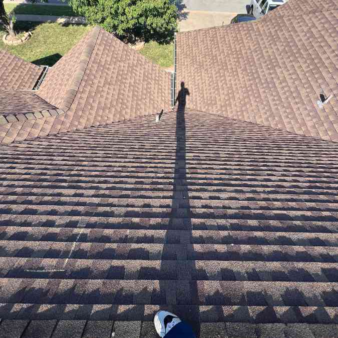 roofer on top of home completing inspection before fixing hail damage on roof in OKC