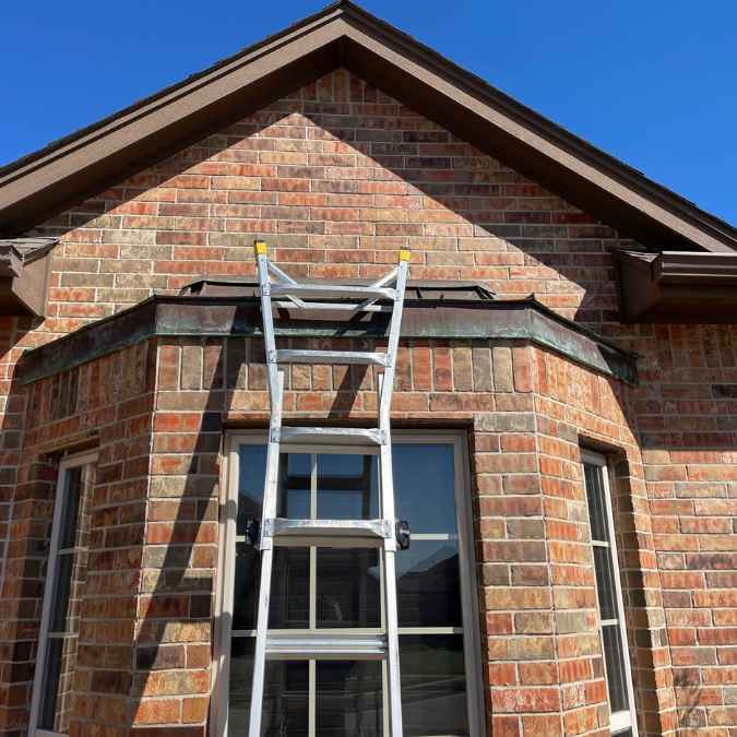 roofer placing ladder on residential home exterior to climb up and inspection roof for hail damage after storm