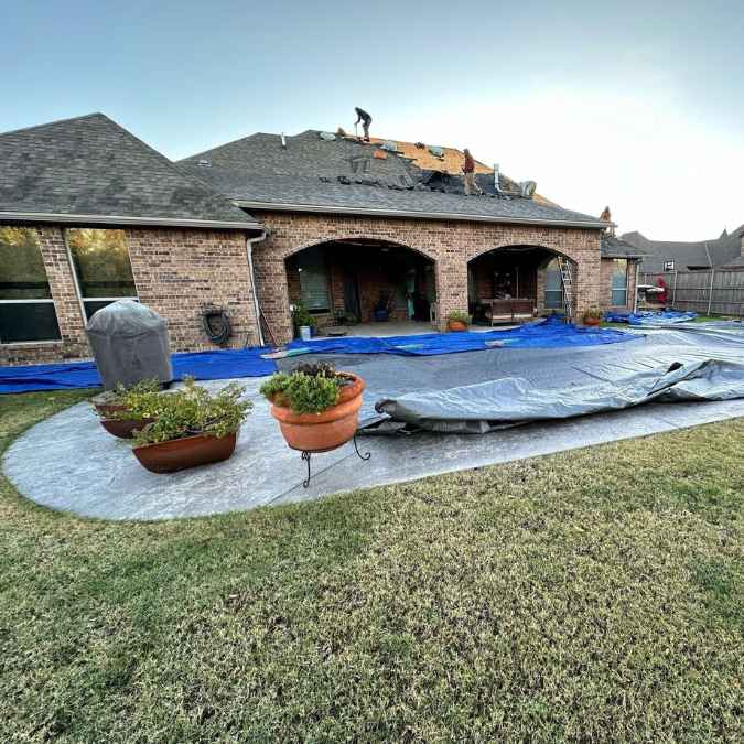 workers on top of home tearing off old decking getting ready for roof installation in Moore, OK