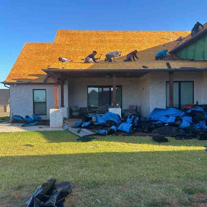 roofers tearing off hail damaged shingles to repair storm damage on residential home in Guthrie, OK