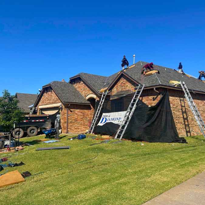 roofing crew removing old shingles on roof to be able to complete full roof replacement after hail storm