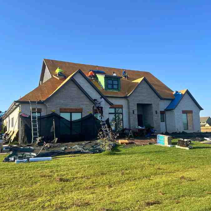 workers removing old roof shingles to install new roof after hail storm in Guthrie, OK