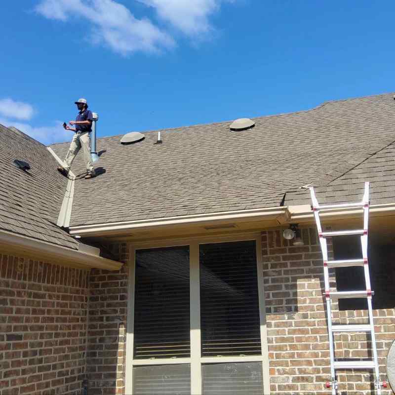 Ladder against residential home with roofer inspecting shingles in Oklahoma City
