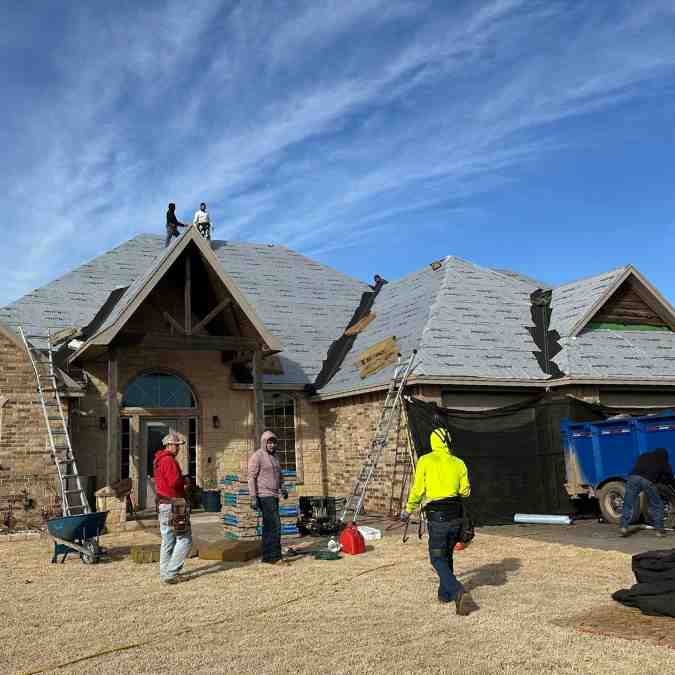 roofers outside of residential home in Shawnee, OK getting ready to remove hail damaged roof