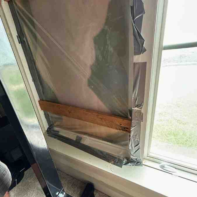 plastic and plywood covering home window after glass was broken during large hail storm in Guthrie, OK