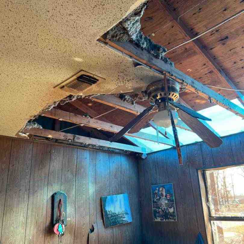 photo showing tornado damage to roof and home