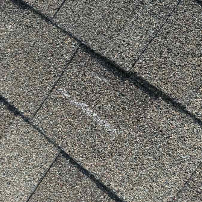 close up of wind damage to grey asphalt shingle found by roofer during inspection on home in Moore, OK